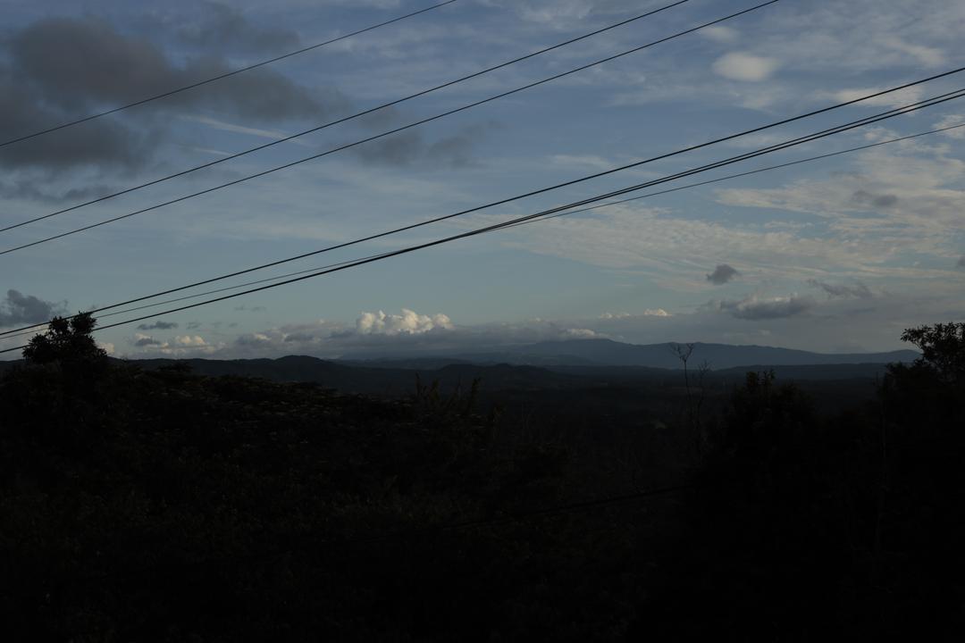夕空と雲の下、電線が横切る山並みの風景